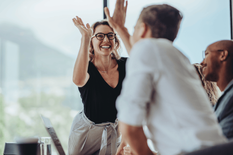 Colleagues in corporate office giving each other a high-five.
