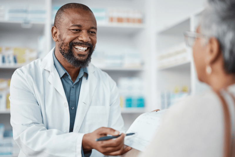 Male pharmacist in discussion with a patient explaining her prescription.