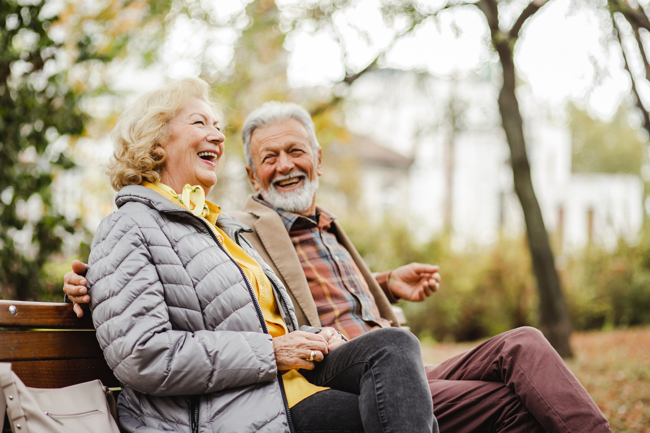 Senior couple sitting on a bench laughing