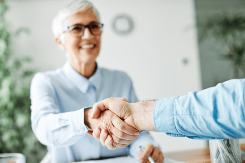 Senior woman shaking hands with someone out of frame