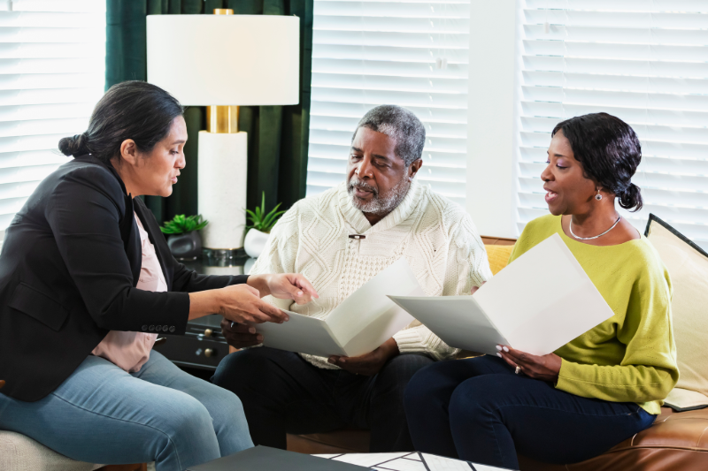 Professional woman sitting explaining things to a senior couple