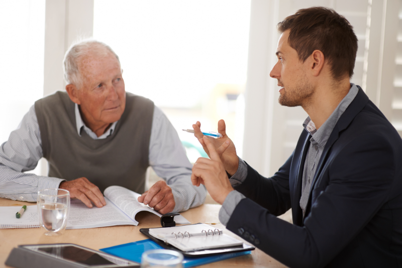 Young man sitting at a table explaining options to a senior man