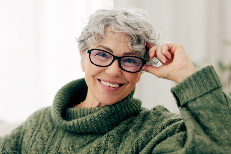 Senior woman with glasses smiling sitting on a couch