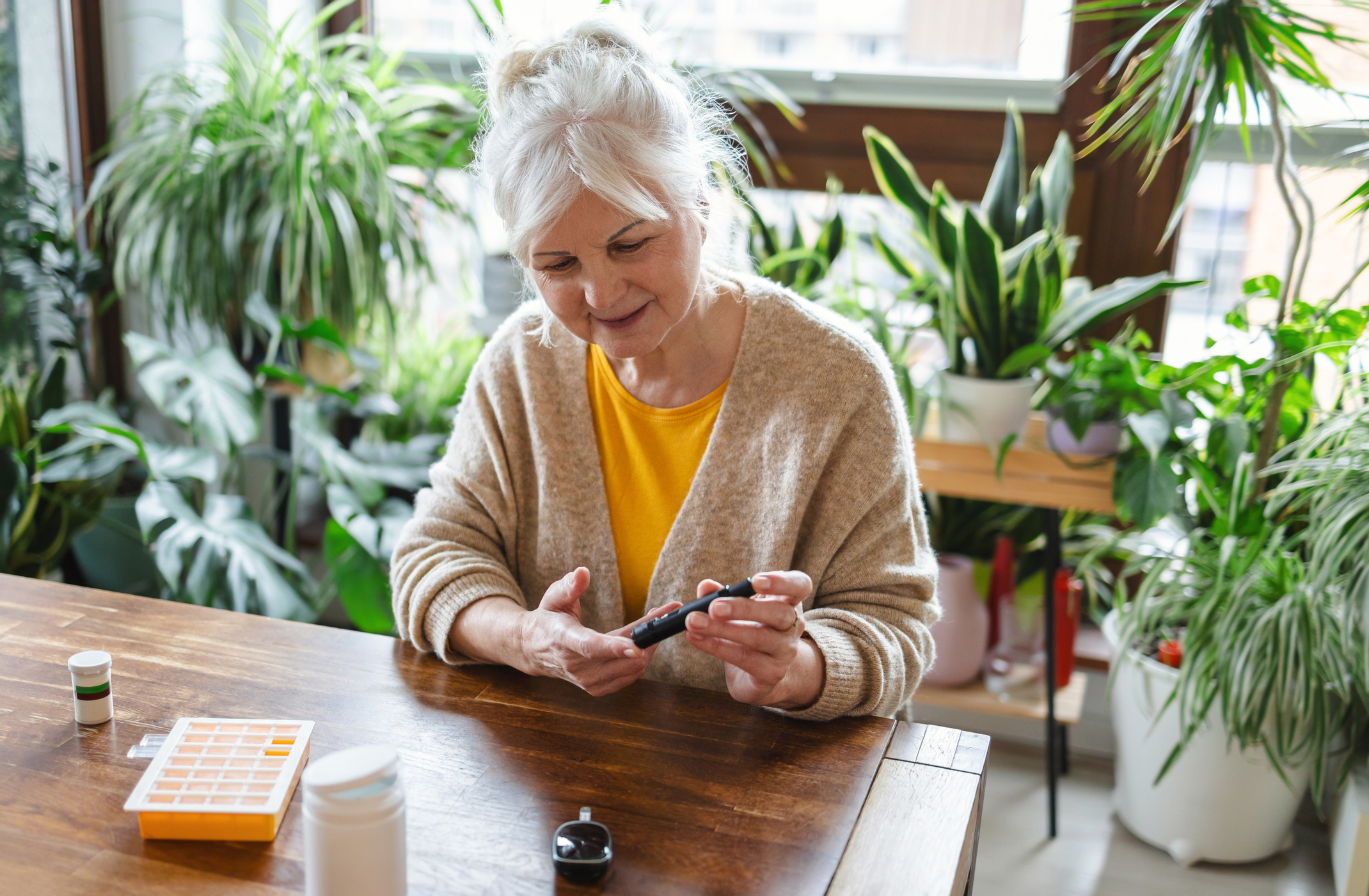 Senior woman sitting at a table checking her blood sugar
