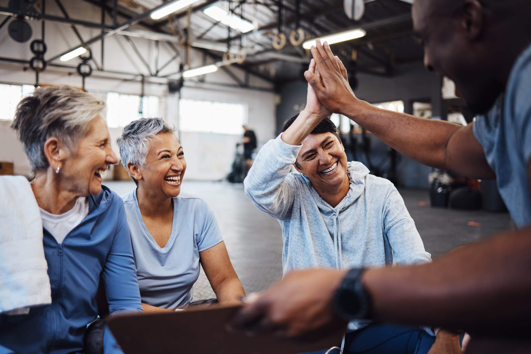 Senior women with personal trainer after a workout giving a high-five to celebrate