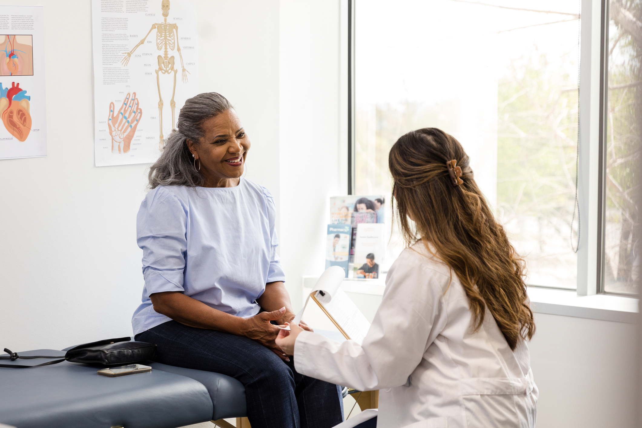 Senior woman sitting on a table at the doctors office with a doctor