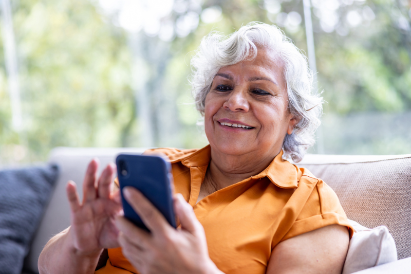 Senior woman sitting on the couch playing on a phone