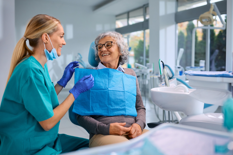 Senior woman sitting in dental exam chair with a dental hygienist