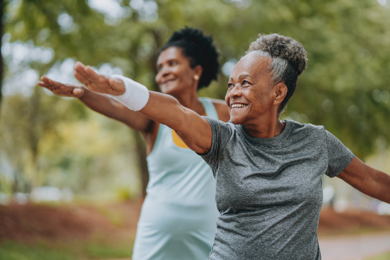 Two African American women doing yoga in a park